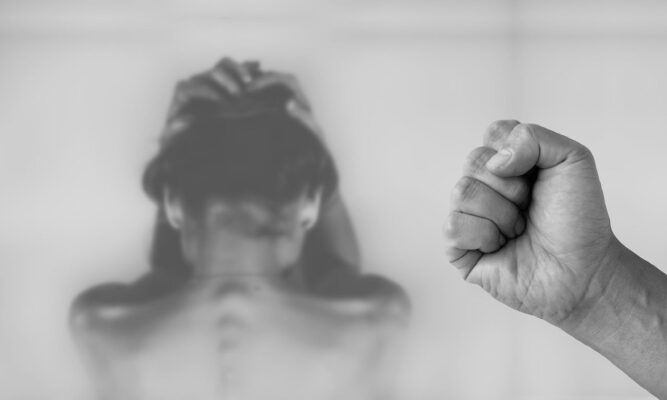 Fist and woman against the wall shrinking from it.