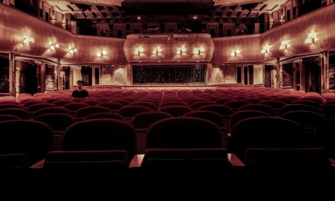 One lone person sits in a dimly lit theater