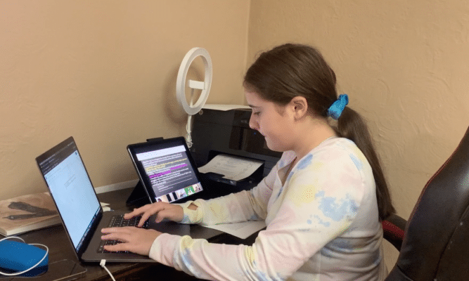 Girl goes to school online in a corner of the living room