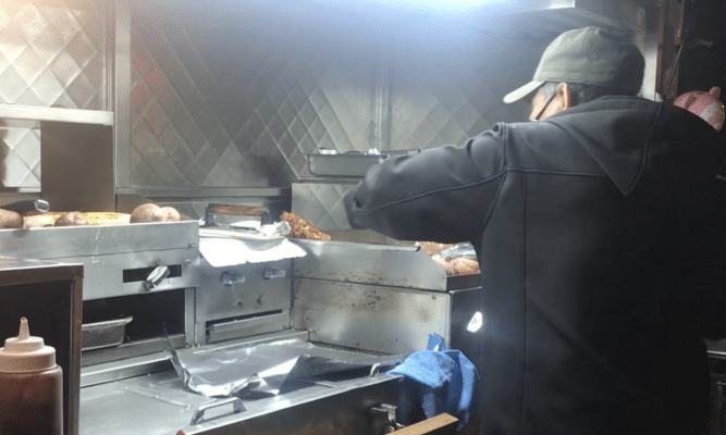 Man prepare food on a cart at night in Jackson Heights, Queens