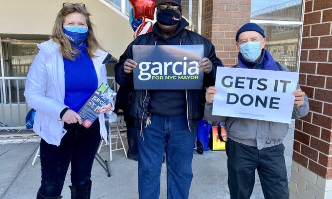 a photo of Kathryn Garcia, NYC mayoral candidate, and two men holding campaign signs for Garcia