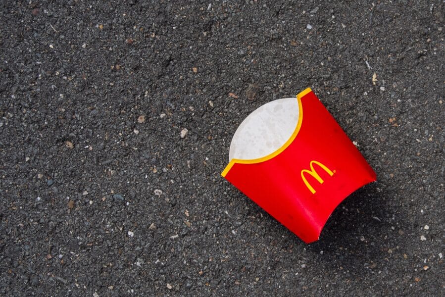 a photo of an empty large McDonald's fries box lying on the road.