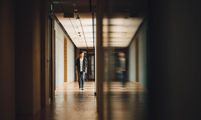 For decorative purpose. Shows a man walking down a hallway in what could be a school environment.