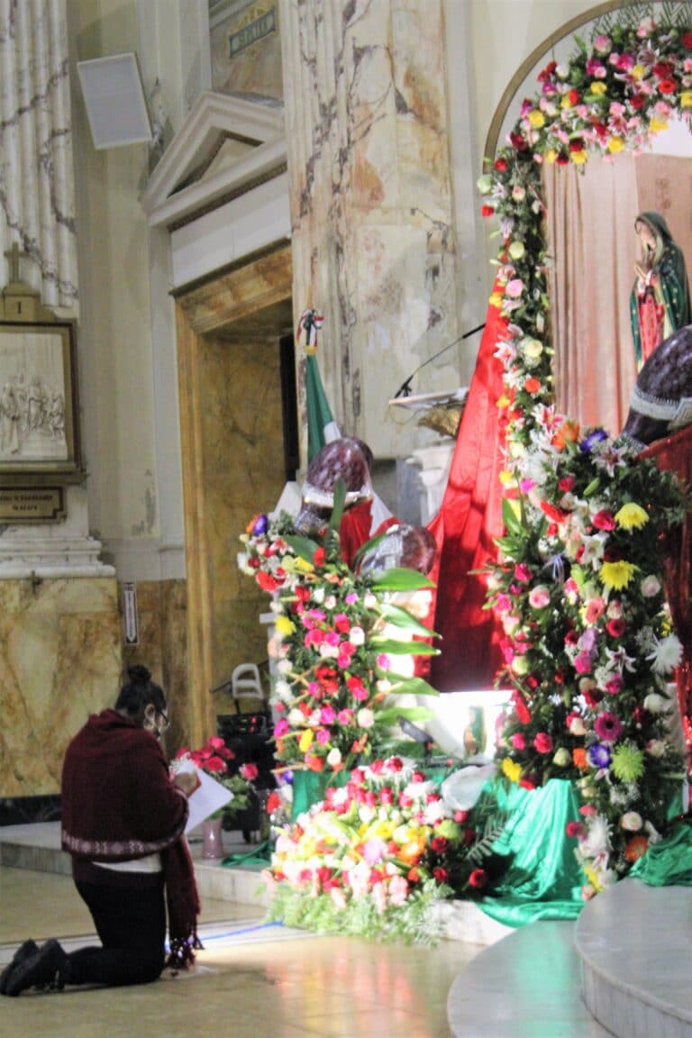 Parishioner kneeling in front of alter leading a prayer.