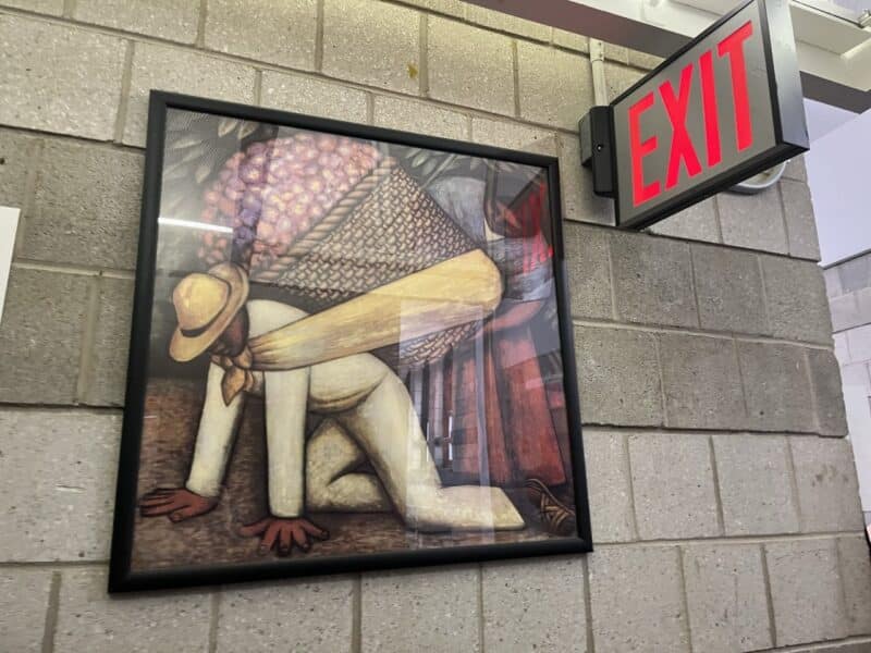 Photo of Latin American workers in a frame hung on a wall near a red exit sign.