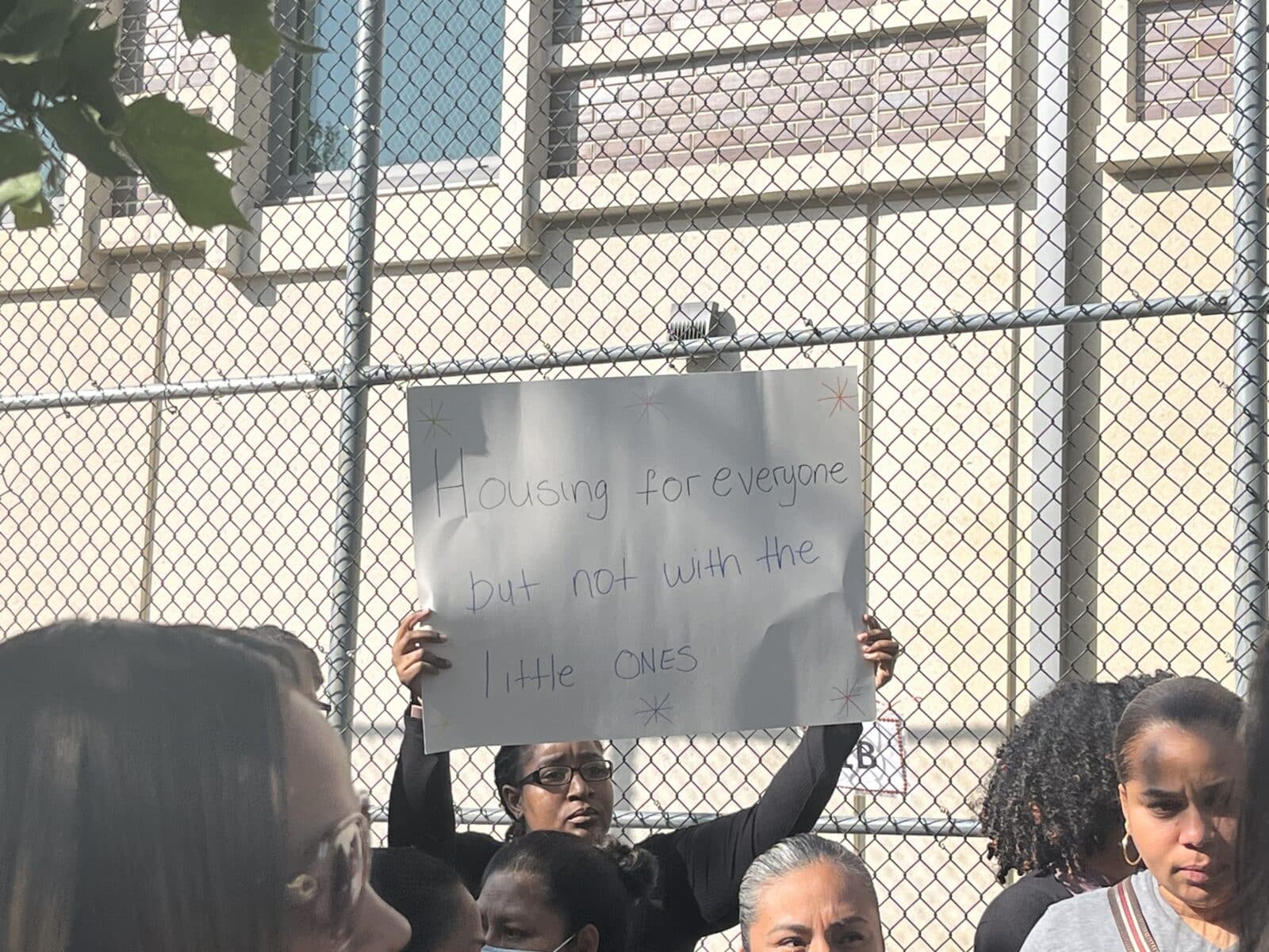 Parent holds up a sign that reads "Housing for everyone but not with the little ones"