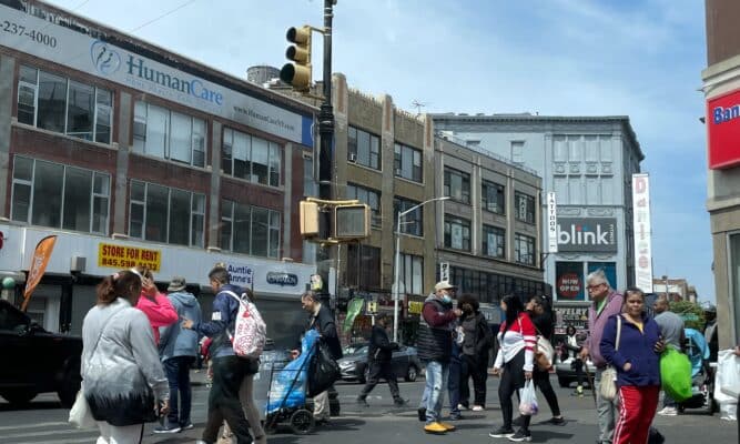 A busy street in the Bronx full of people going about their business.